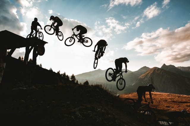 Sequence photo of a rider jumping at sunset, silhouetted over the Livigno mountains