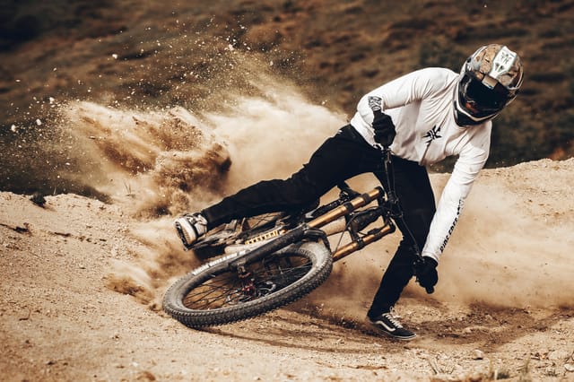 Downhill rider railing a dusty berm in a full-face helmet — Mottolino Bikepark, Livigno